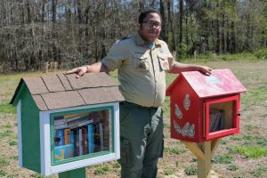 image of Eagle Scout standing with two little library boxes installed on posts, filled with books