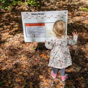 Child standing in front of StoryWalk Board with back to camera. 