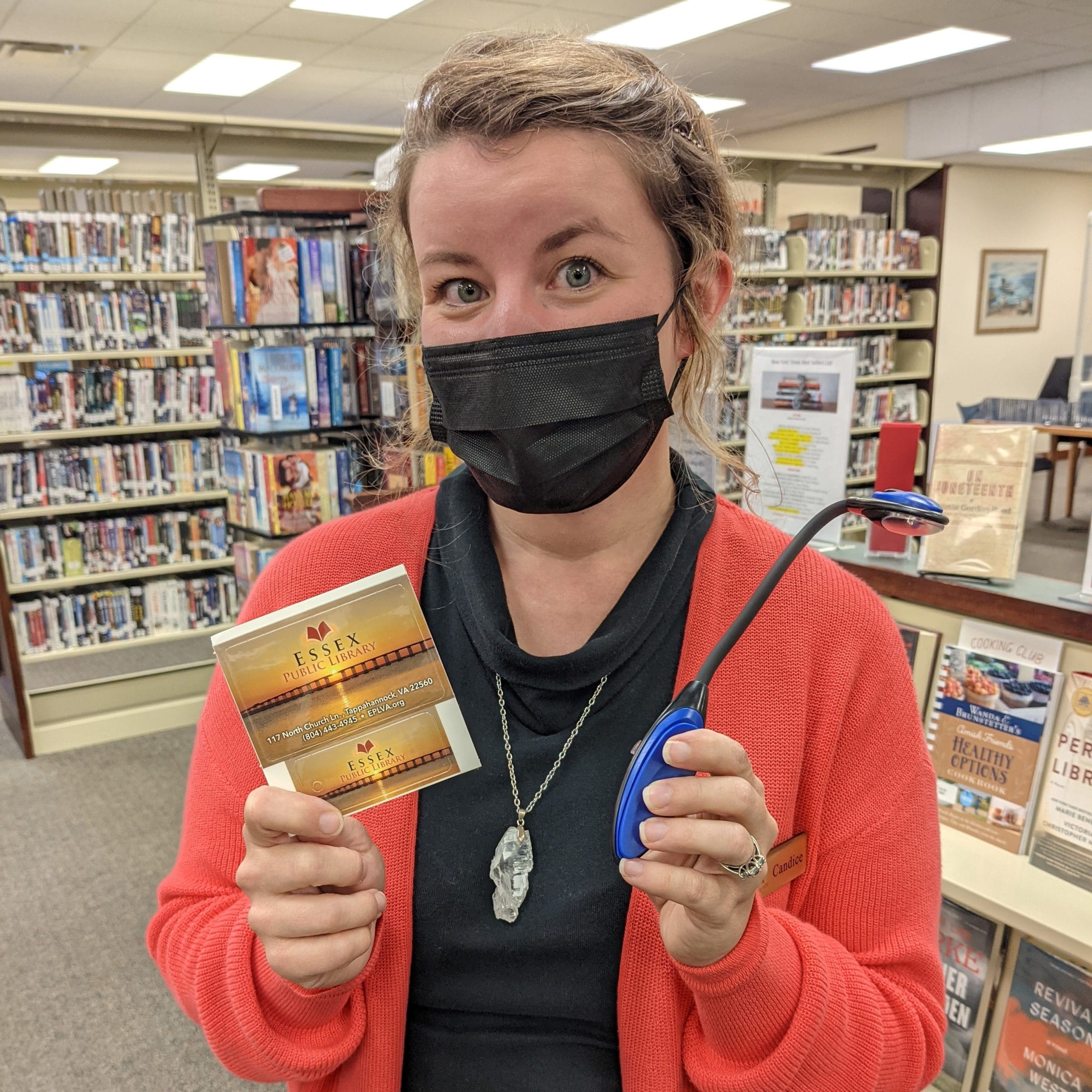woman holding book light and library card